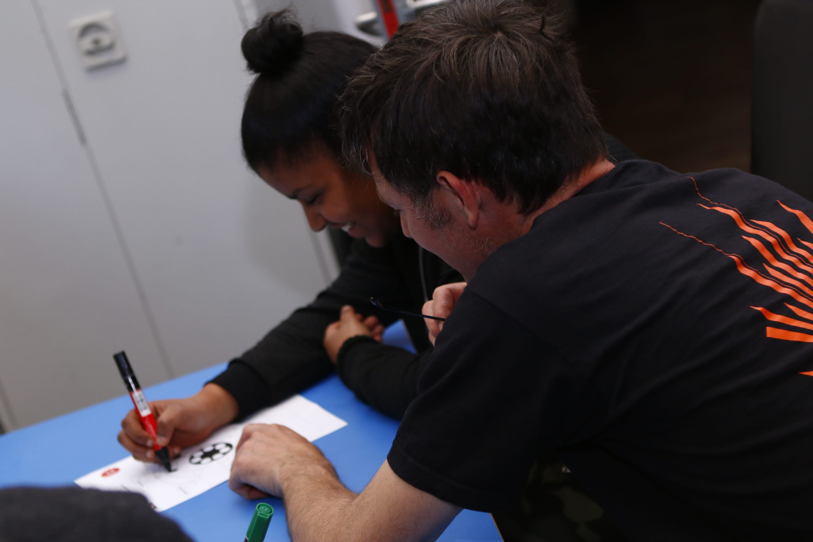 A member of staff helps a young woman to fill in paperwork
