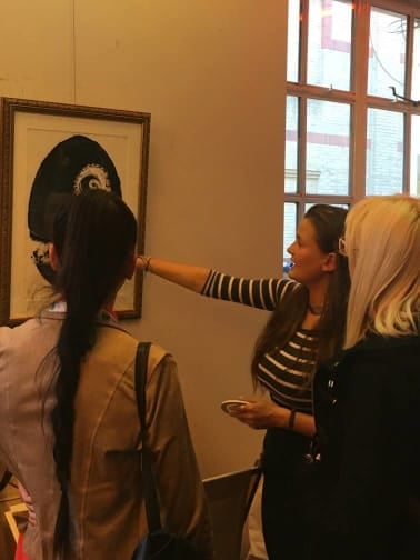 Three people enjoying one of the displays at an art exhibition